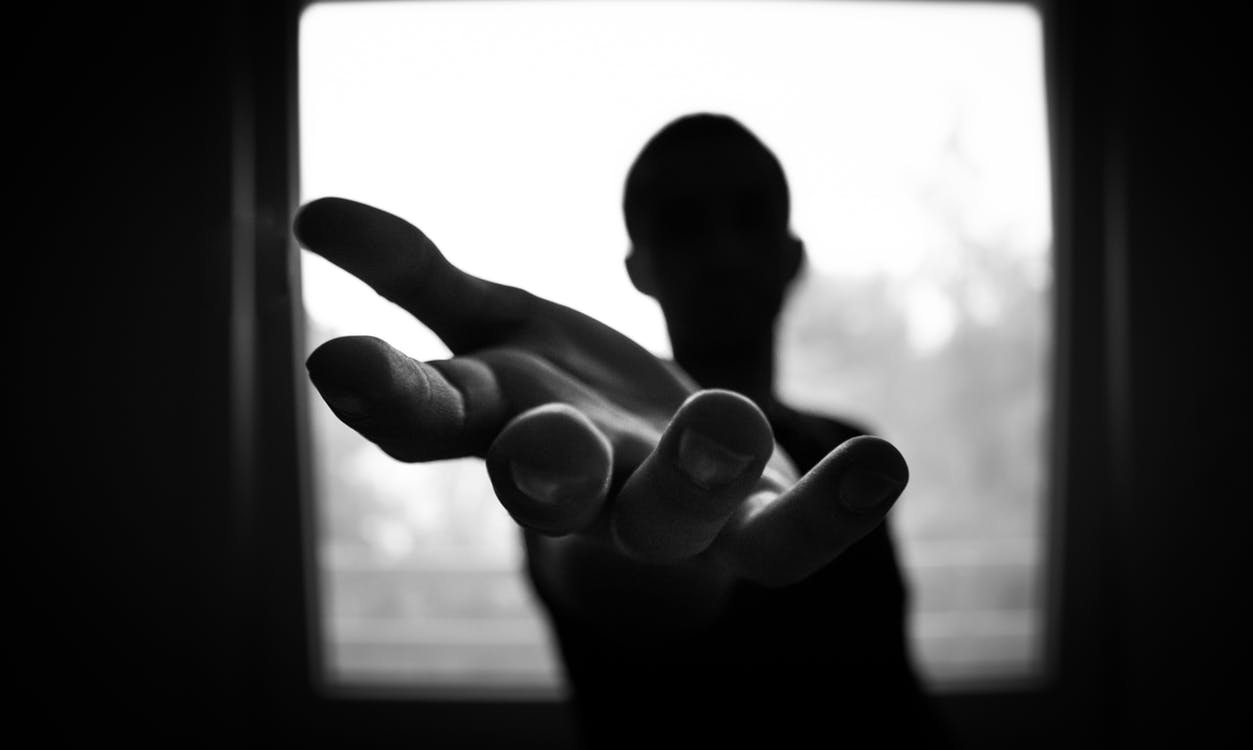 Black and white image of silhouette of person reaching hand out